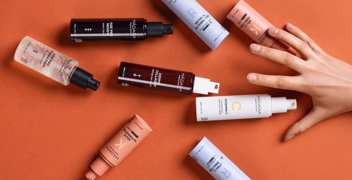 MÁDARA targeted skincare products displayed on an orange background with a hand reaching toward them