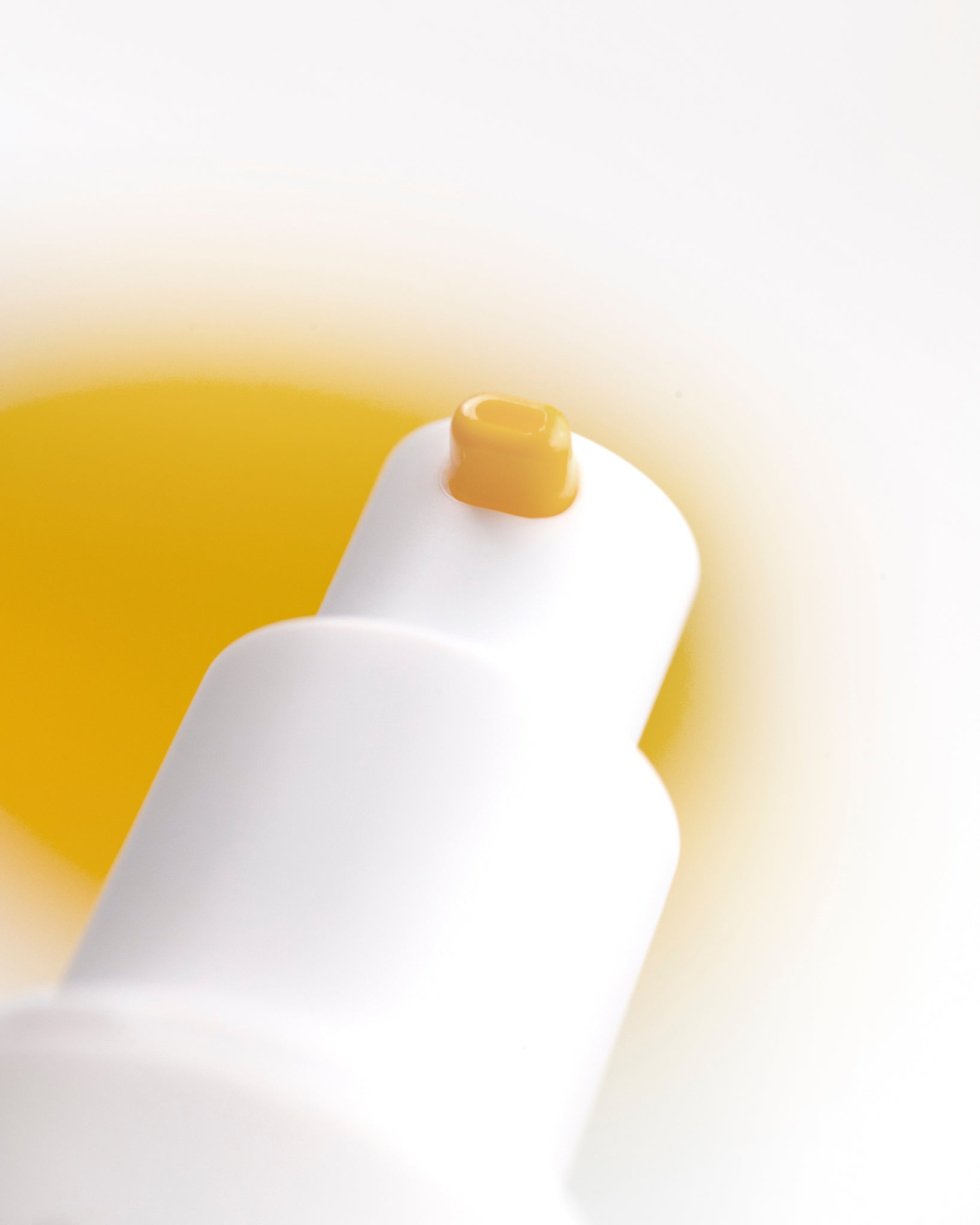 White spray bottle with a yellow cap on a gradient yellow background