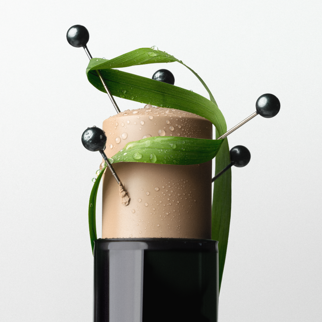 Close-up of a MÁDARA CC Go stick wrapped with green leaves and water droplets