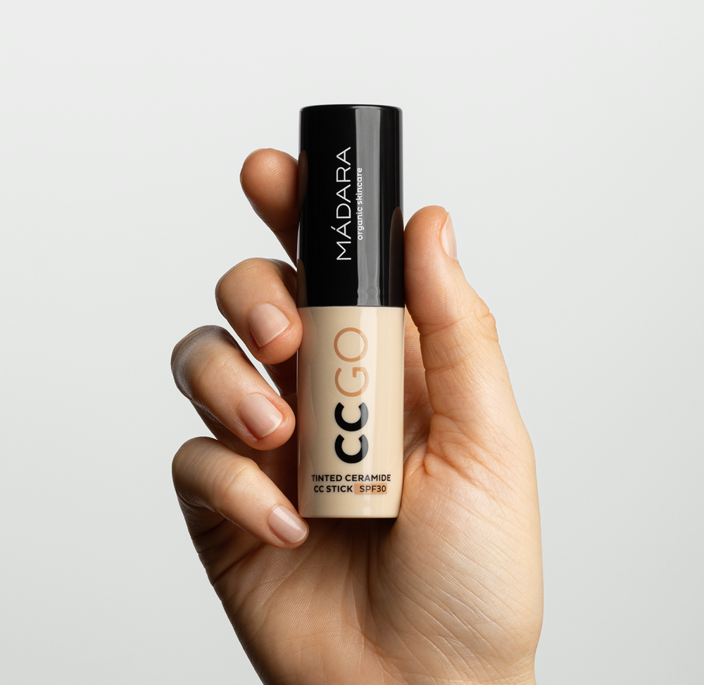 Hand holding MÁDARA CC GO Tinted Ceramide CC Stick SPF30, a portable complexion stick for lightweight coverage and sun protection