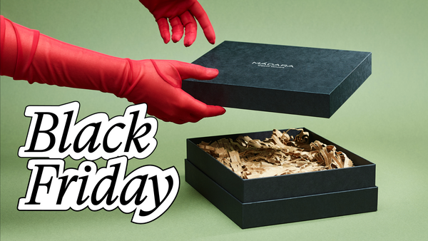 MÁDARA black friday black gift box being opened by hands in red gloves against a green background