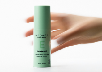 MÁDARA Exosome Longevity Radiance Peptide Serum bottle with blurred hand movement in the background