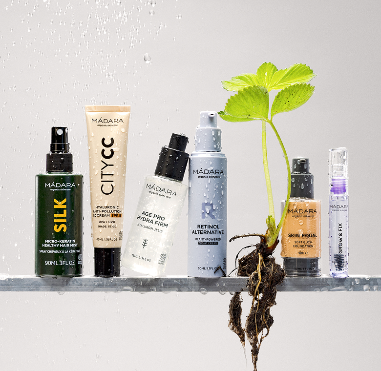 MÁDARA product lineup with City CC cream, retinol alternative, Hydra Firm serum, foundation and Grow & Fix serum under water droplets with fresh plant roots