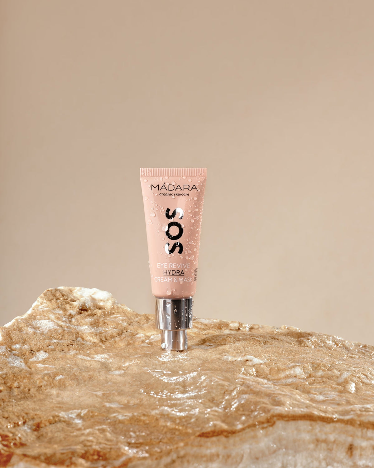 MÁDARA SOS Eye Cream Mask tube resting on a wet rock.