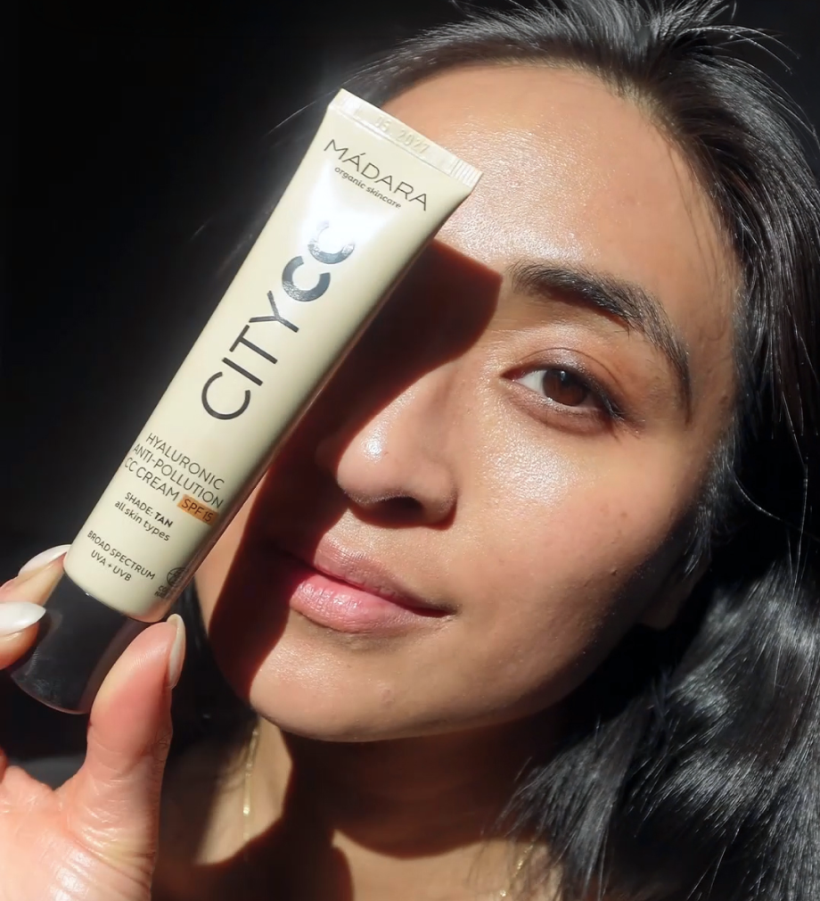 Woman holding MÁDARA City CC cream beside her face in sunlight