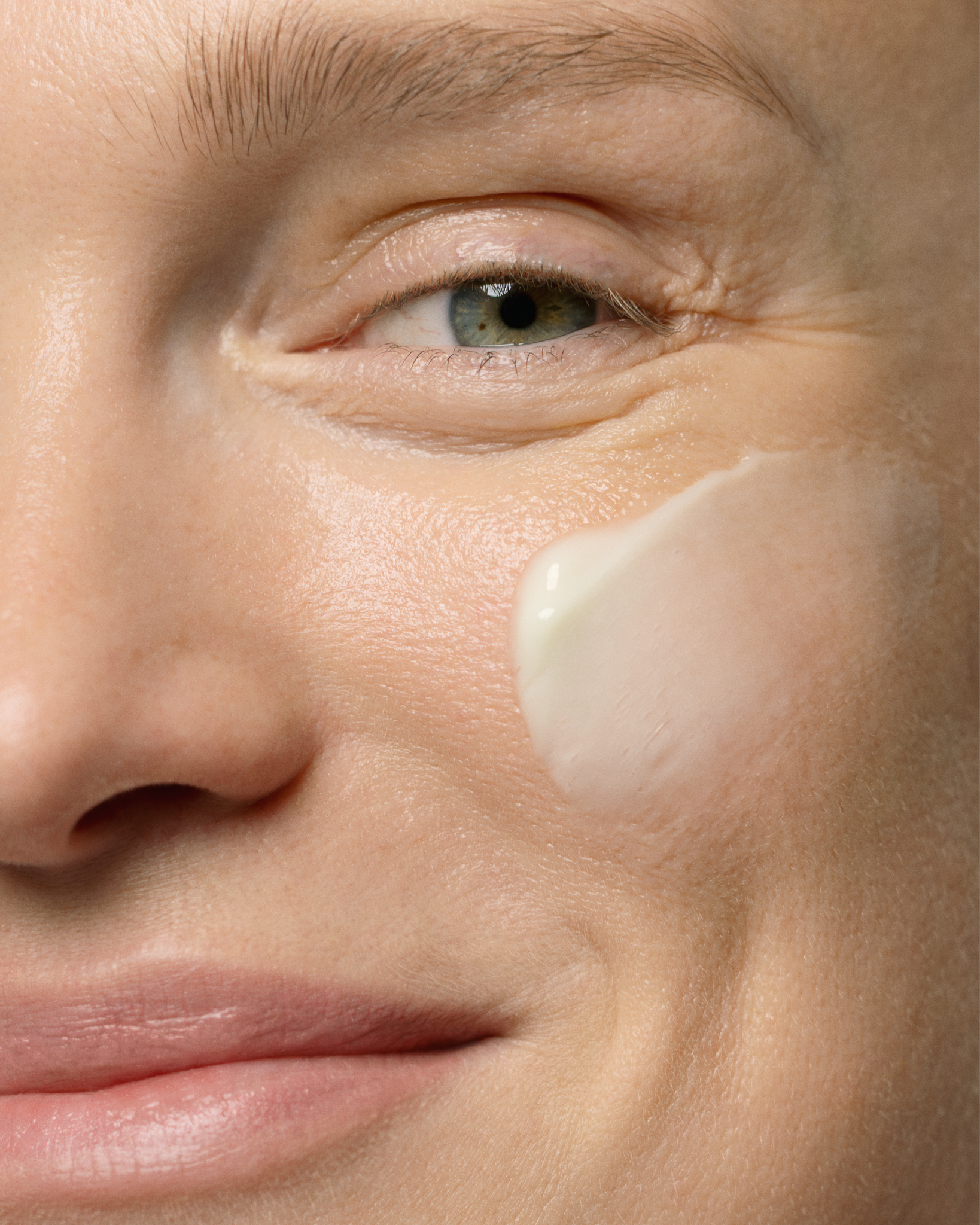 Close-up of a person's face with a skincare product applied to the cheek.