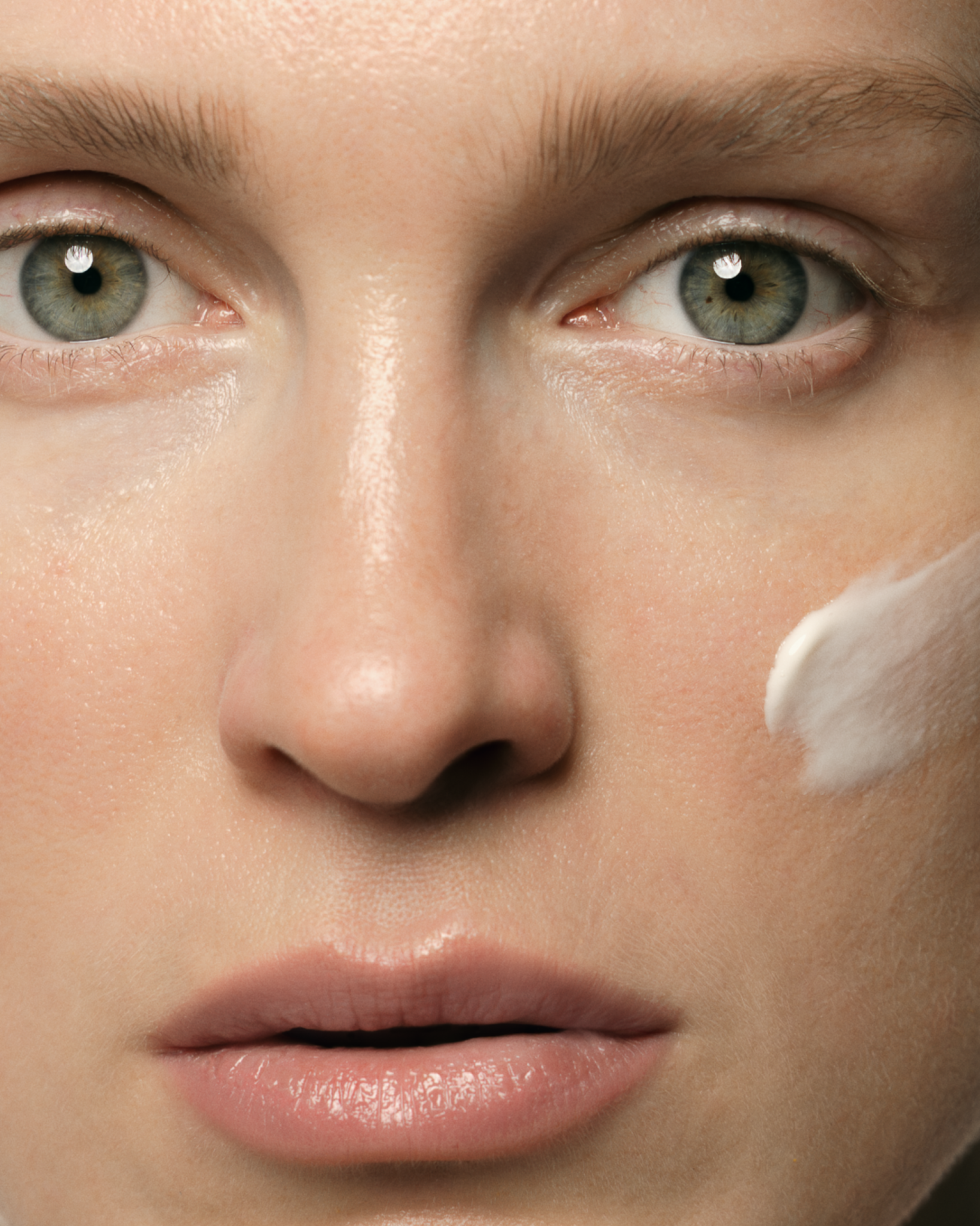 Close-up of a person's face with a white cream applied to the cheek.
