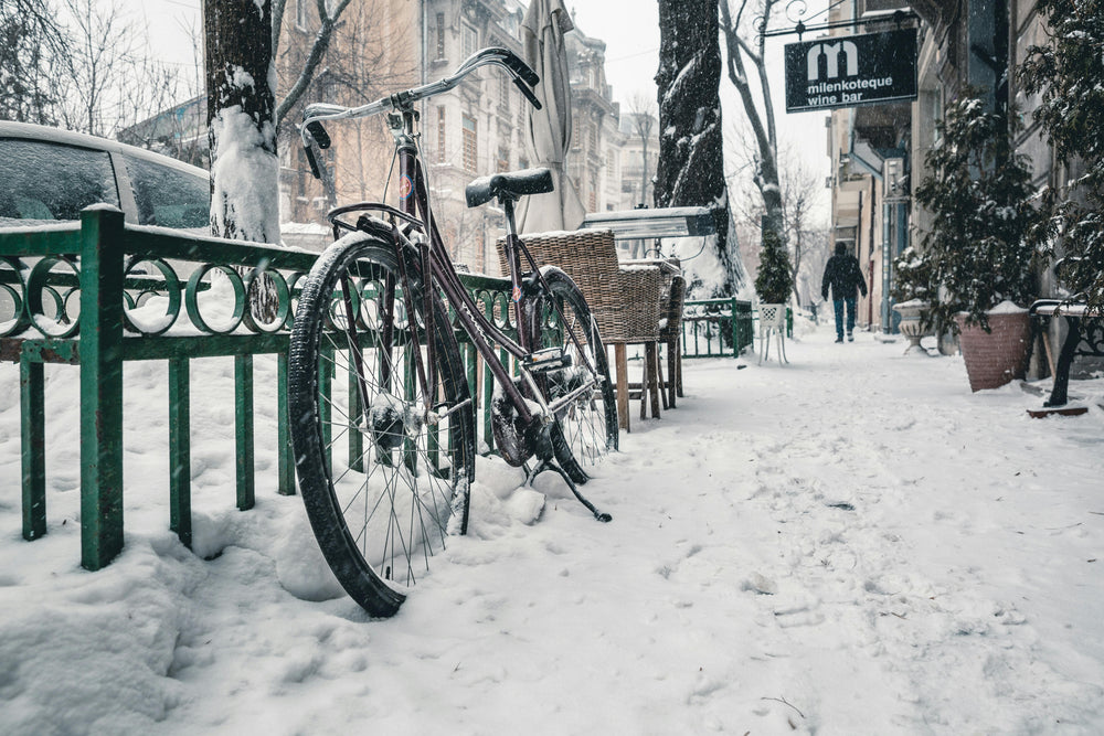 Snow-covered street in Bucharest featuring a bicycle with buildings in the background
